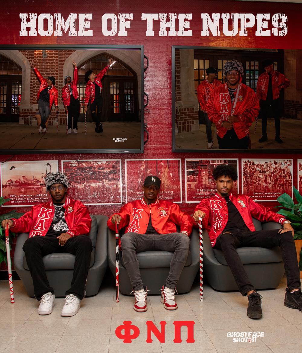 Group photo in front of 'Home of the Nupes' sign wearing matching red jackets.