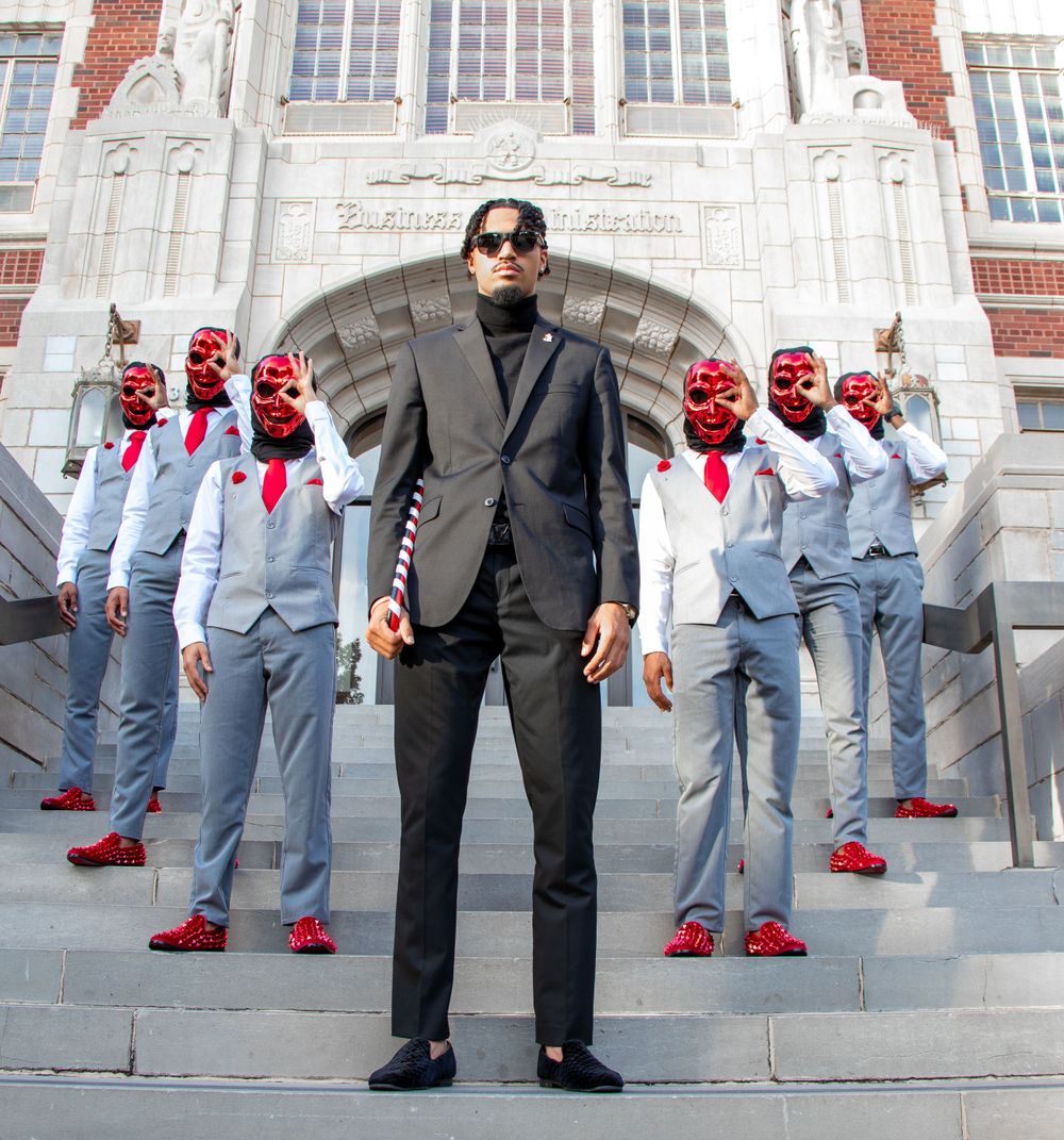 Formal group photo on university steps with coordinated grey suits and red accessories.