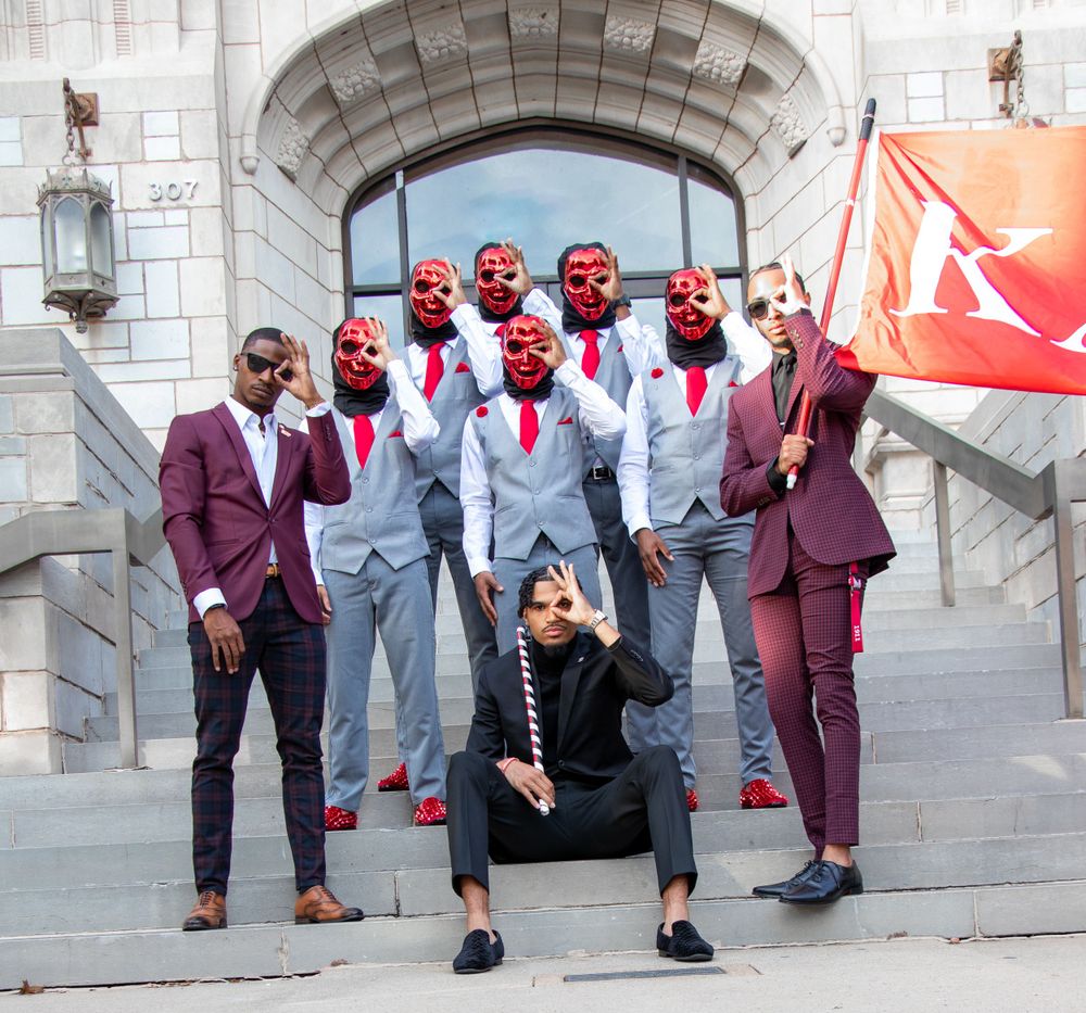Group in formal attire poses on stone steps outside historic building.