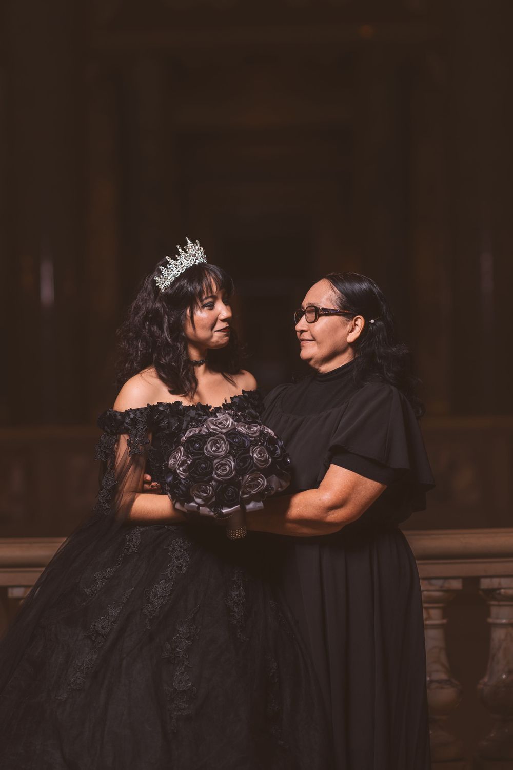 Candid moment captured during formal portrait session in dark, dramatic lighting.