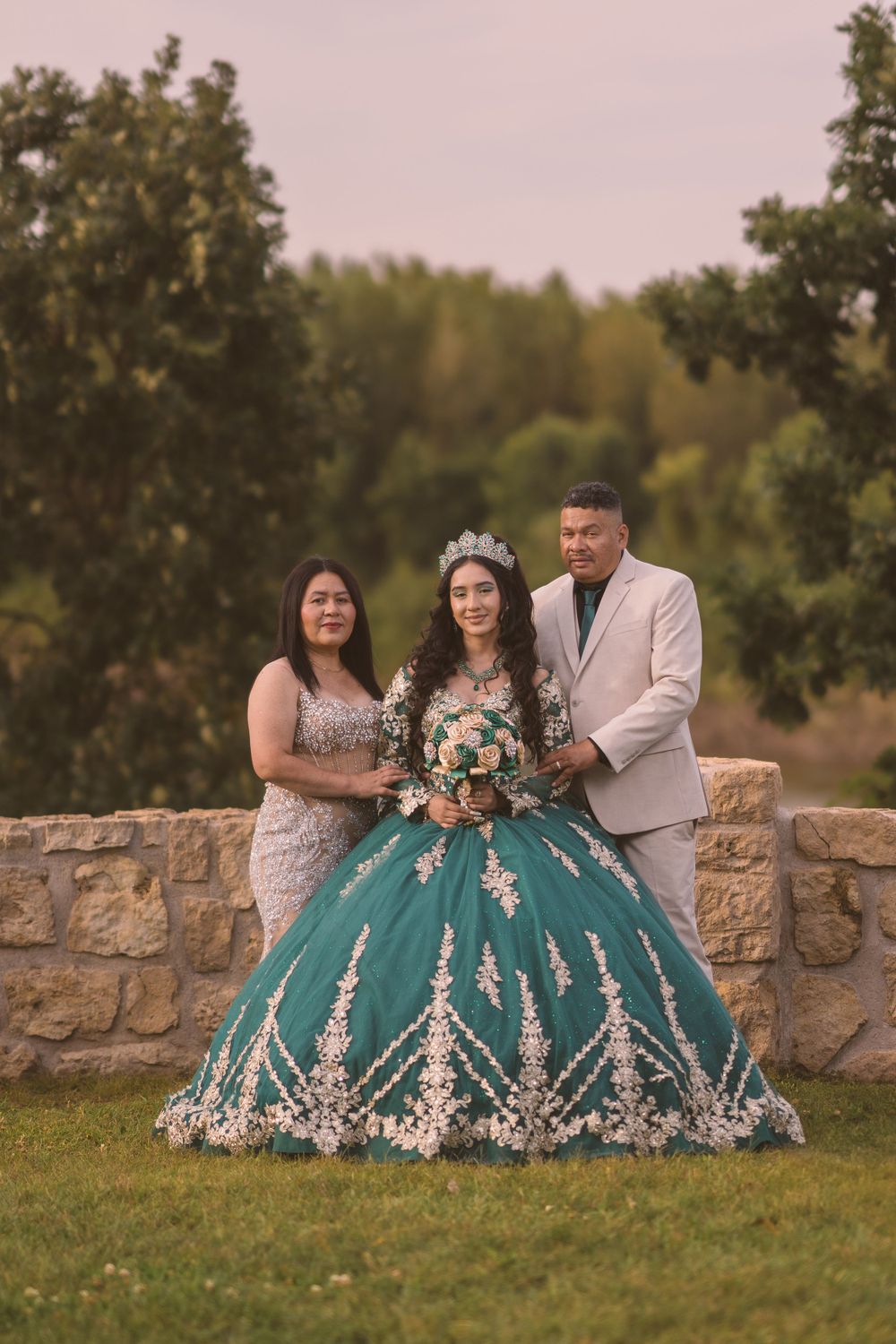 Outdoor family portrait session on stone wall featuring teal and white formal attire.