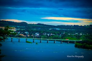 Wide panoramic view of a coastal town and bridge across blue waters.