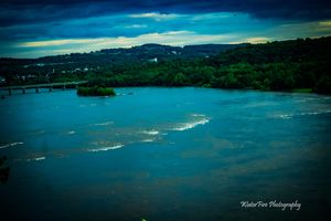 Aerial view of coastal waters and shoreline under dramatic cloudy skies.