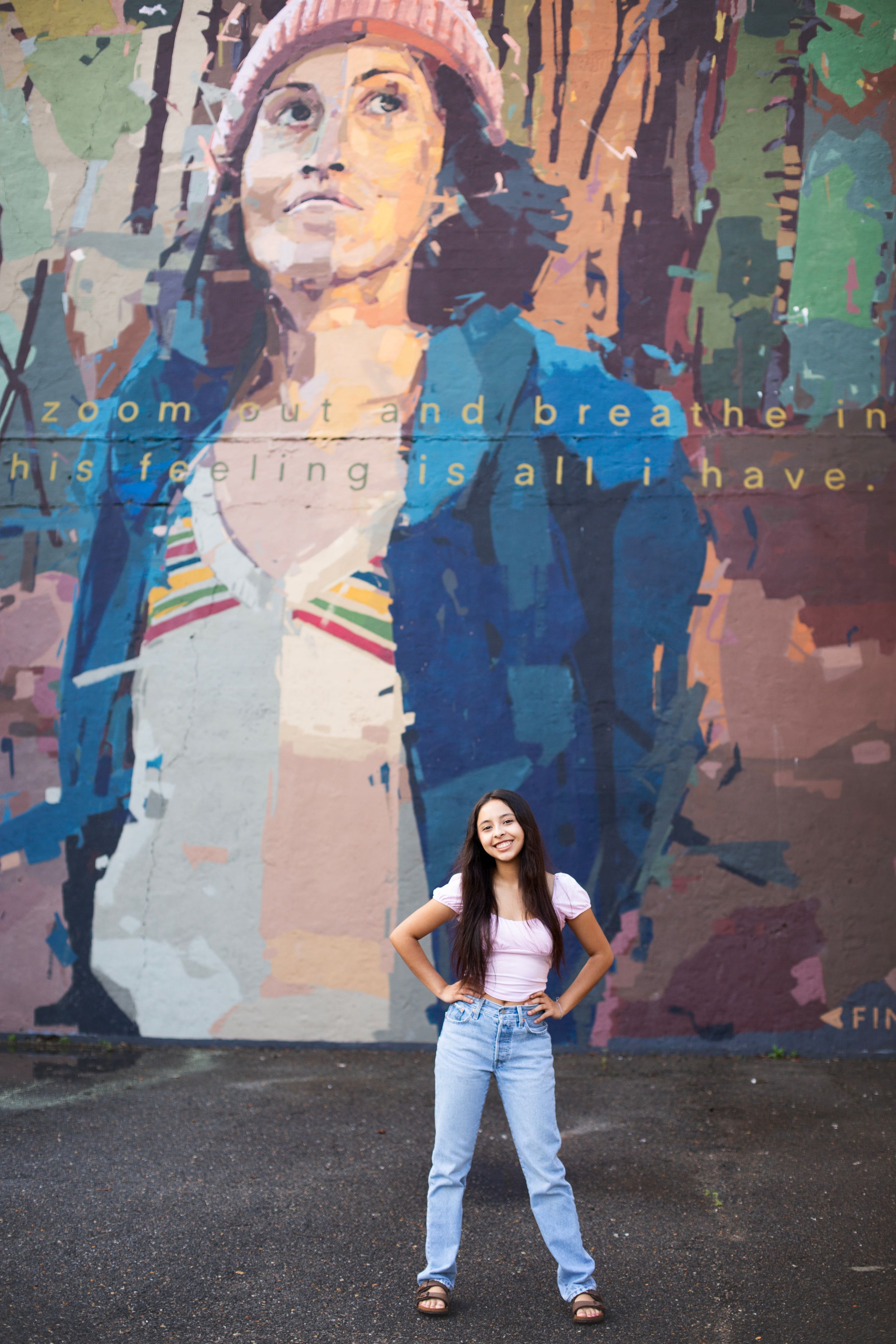 Senior girl standing in front of a graffiti wall.