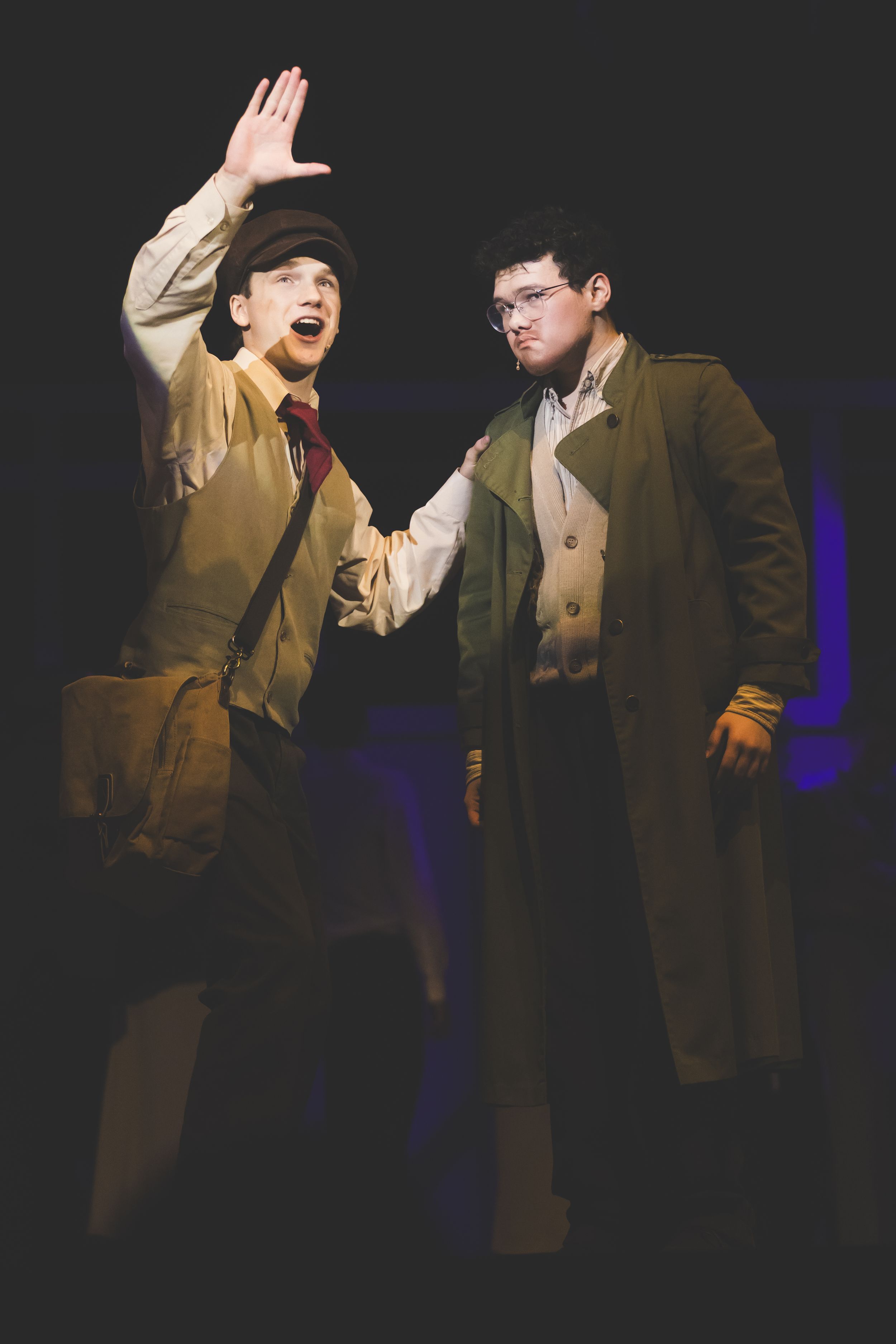 Dramatic stage performance with actors in period costumes against dark background.