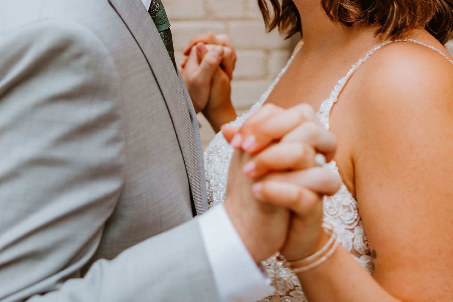 Close-up shot of a couple holding hands while dancing at their wedding reception.