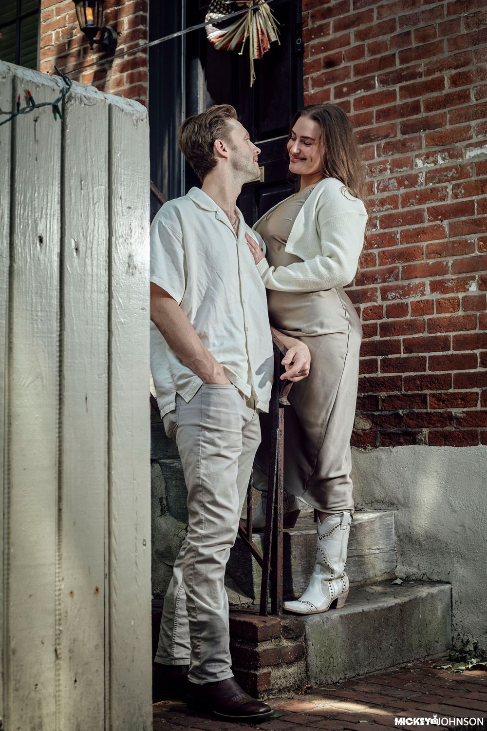 Two people in white clothing share an intimate moment on brick steps.