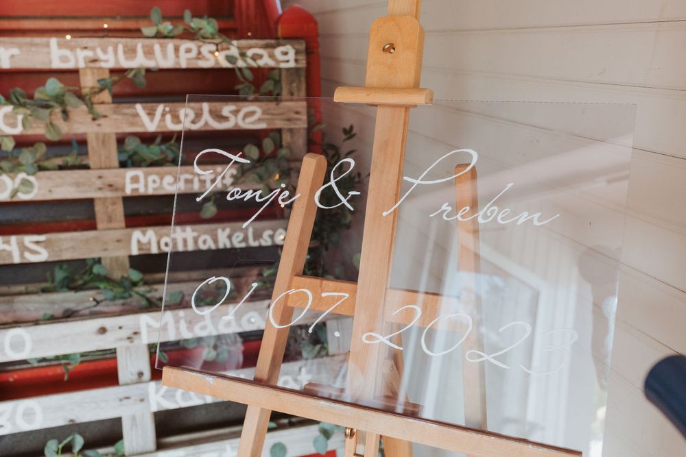 Wedding signage displayed on a wooden easel against white wall.