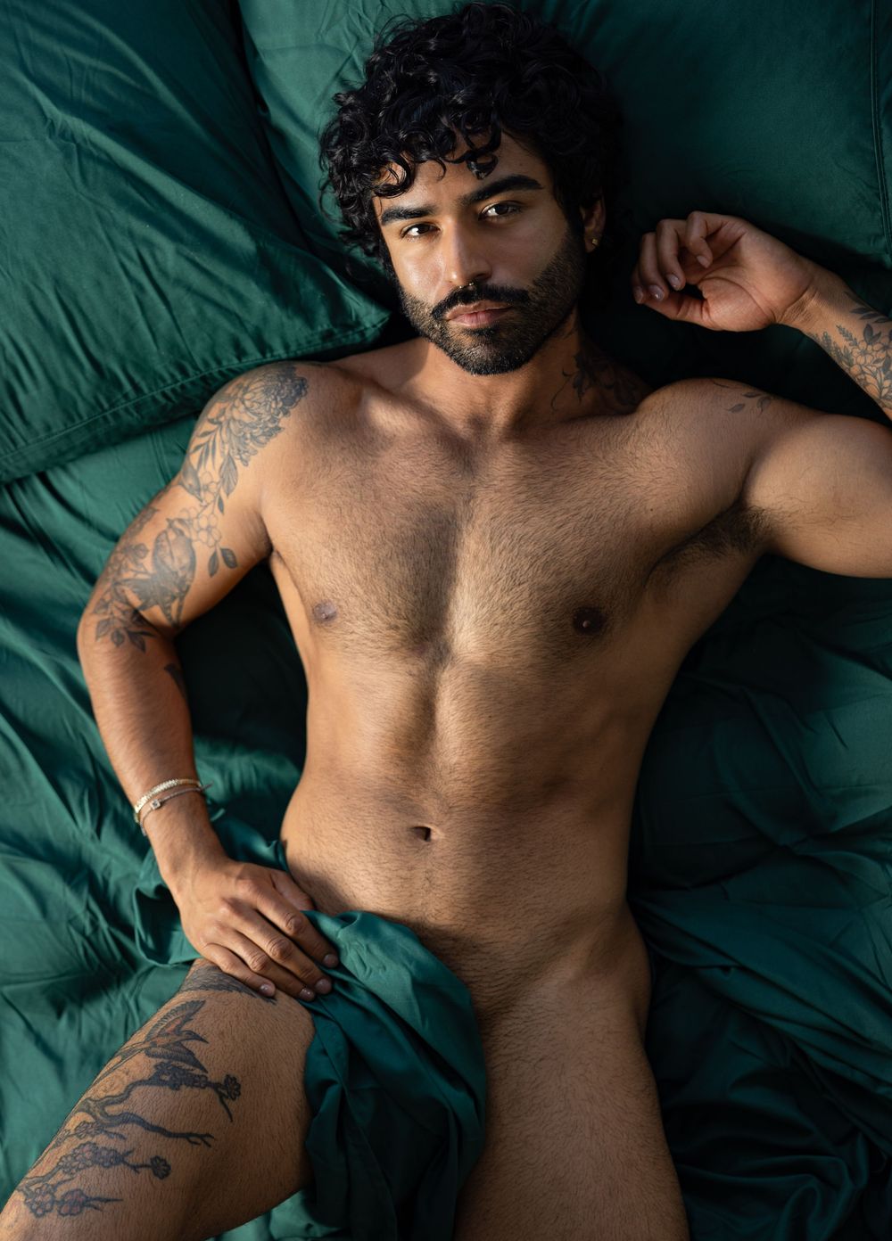 Overhead photo of man naked in bed covered only with a bedsheet during boudoir photo shoot with Los Angeles photographer.
