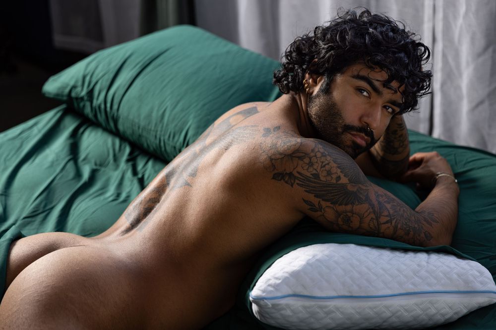 Naked man lying on stomach with rear end exposed captured during boudoir photo shoot in Los Angeles studio.