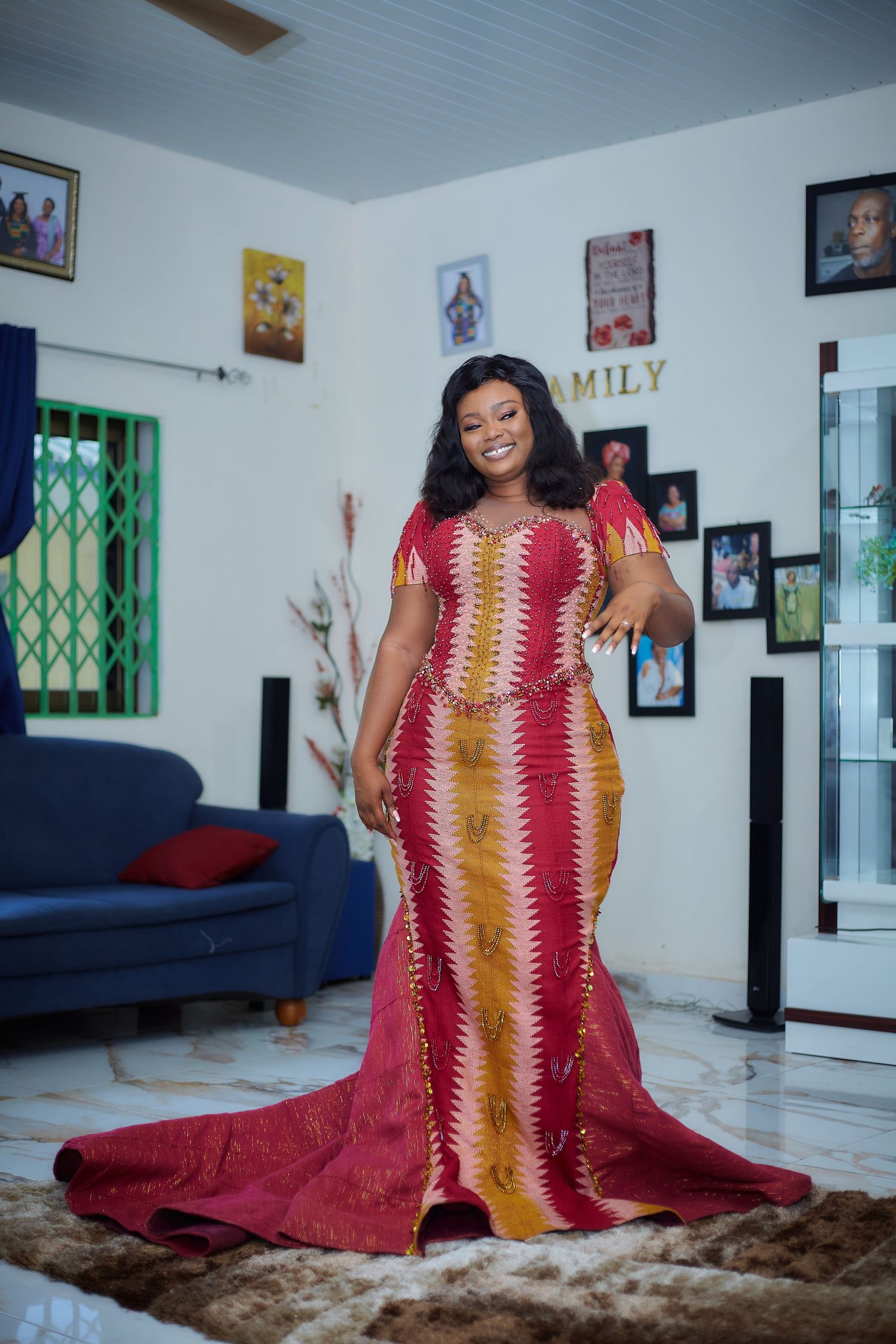 Beautiful dress with vibrant red and orange chevron pattern features a dramatic floor-length train in a modern living room setting.