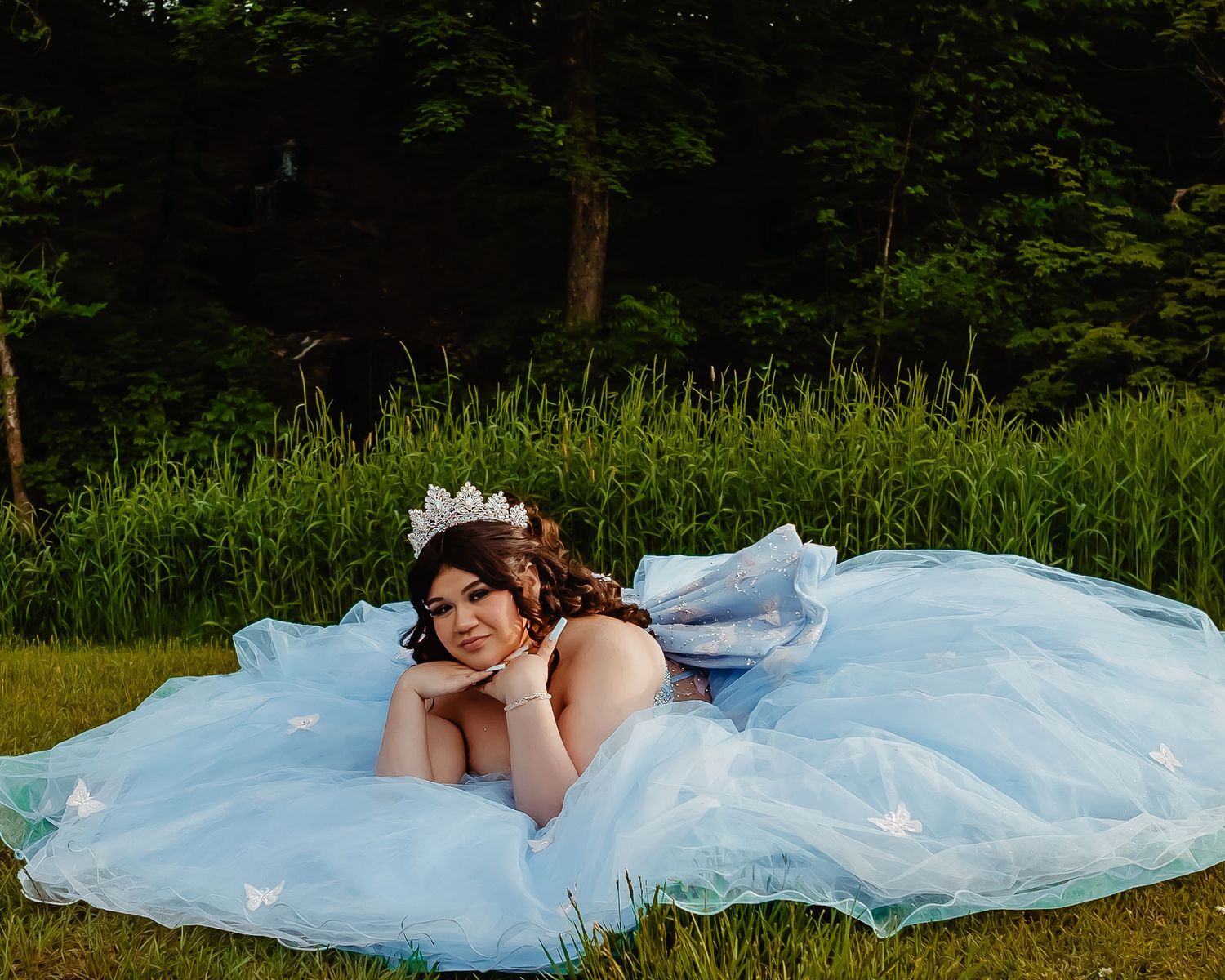 Light blue princess ball gown spread out beautifully on green grass in a garden setting.