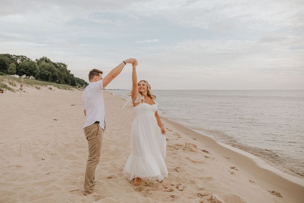 Couple dancing gracefully on beach with ocean waves in background.