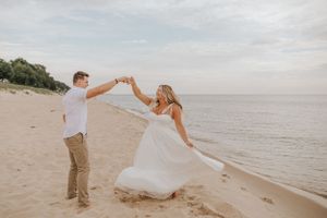 Playful dance moves captured on sandy beach with ocean view.