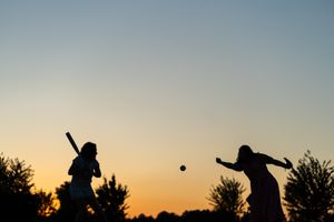 Mother pitching softball to daughter at sunset in Redmond.