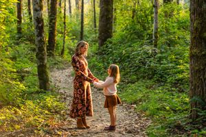 Mother and daughter holding hands in the forest in the summer.