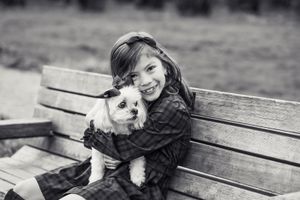 Black and white photo of girl holding her dog.