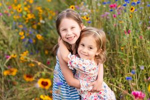 Sisters hugging and smiling in a flower field in Woodinville.