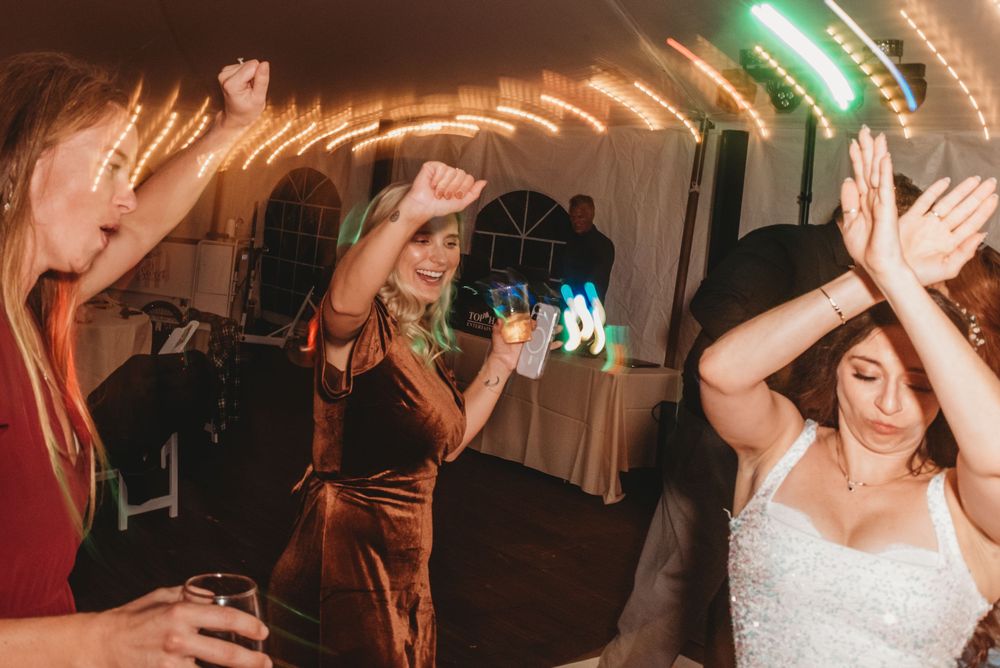 Wedding guests dance and celebrate on a dimly lit dance floor during an evening reception party.
