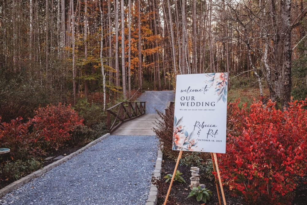 Autumn forest path with red foliage and directional signs along a gravel walkway.