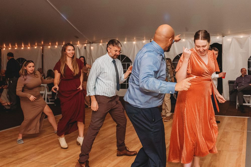 Couples dancing together at a social event with string lights visible in the background.
