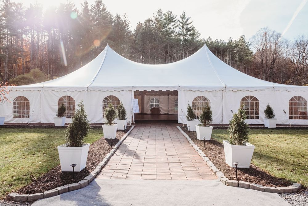 White wedding tent pavilions set up outdoors with stone walkways and landscaping for an elegant event venue.