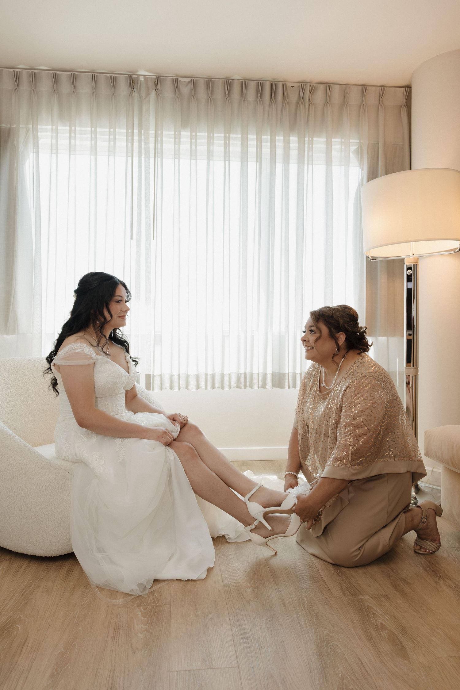 Interior scene with white curtains and hardwood floors showing wedding day preparations.