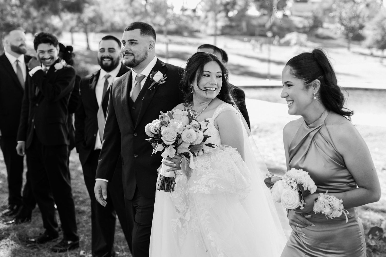 Wedding party members smile during an outdoor ceremony.