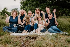 Family group relaxing together on grassy ground during an outdoor photoshoot.