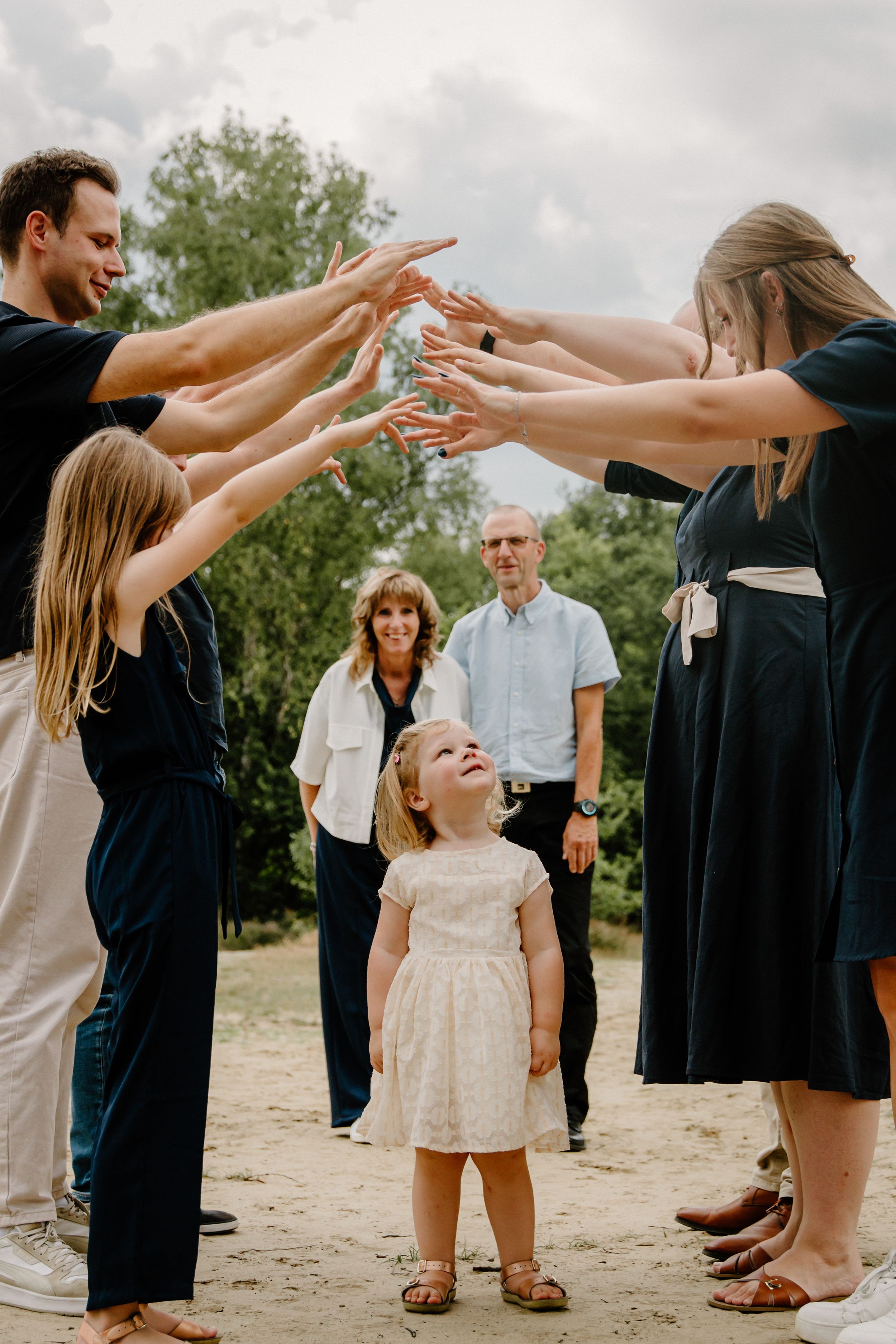 Group playing a fun game with hands reaching out in an outdoor setting.