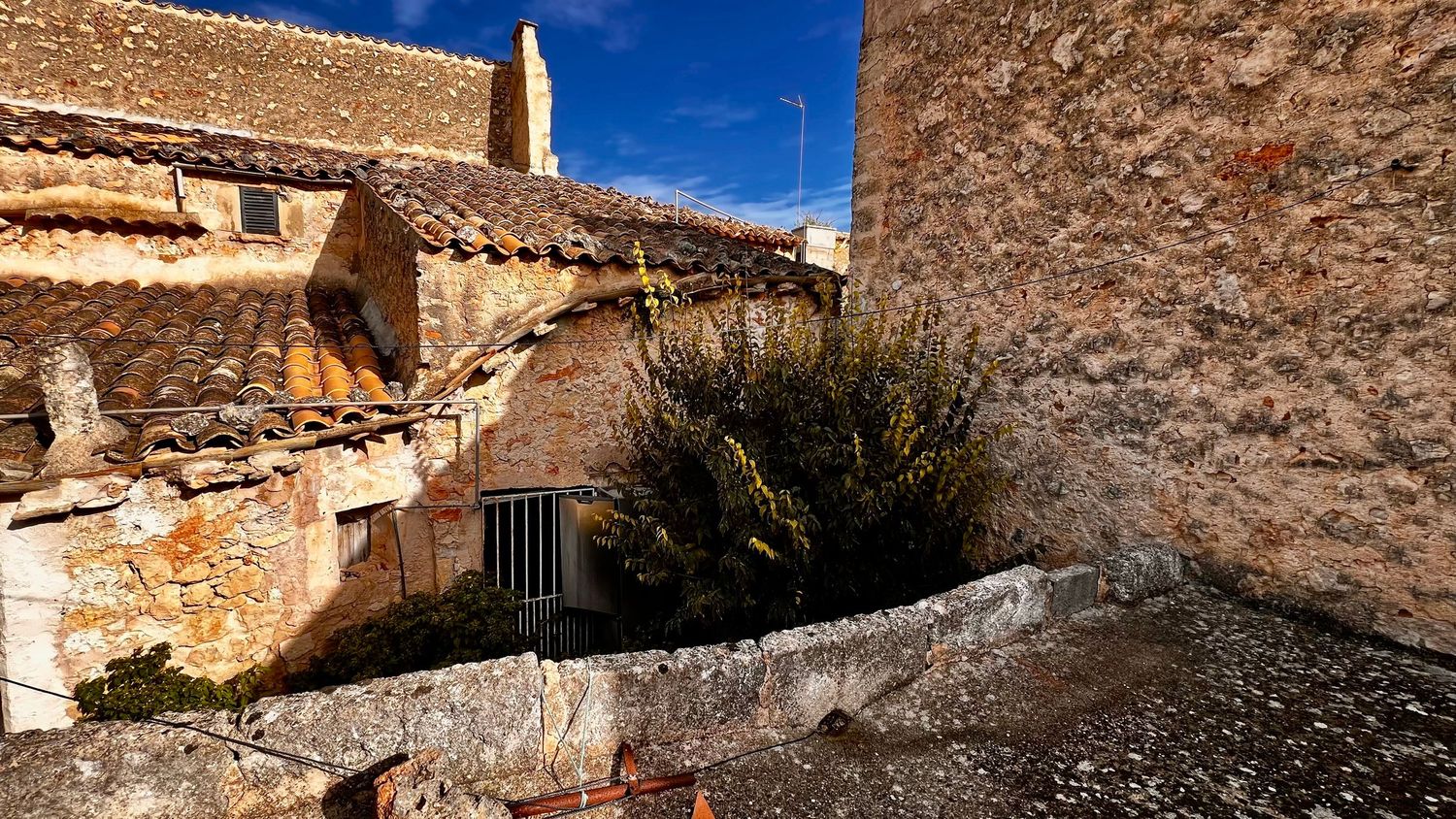 Ancient stone buildings with terracotta roof tiles and rustic walls under a clear blue sky in a historic village.
