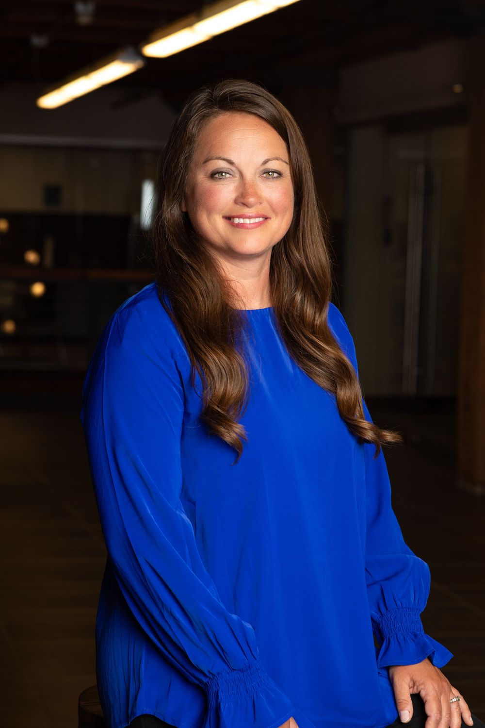 Professional headshot of a female wearing royal blue taken in an office space in the United Building in Sioux City