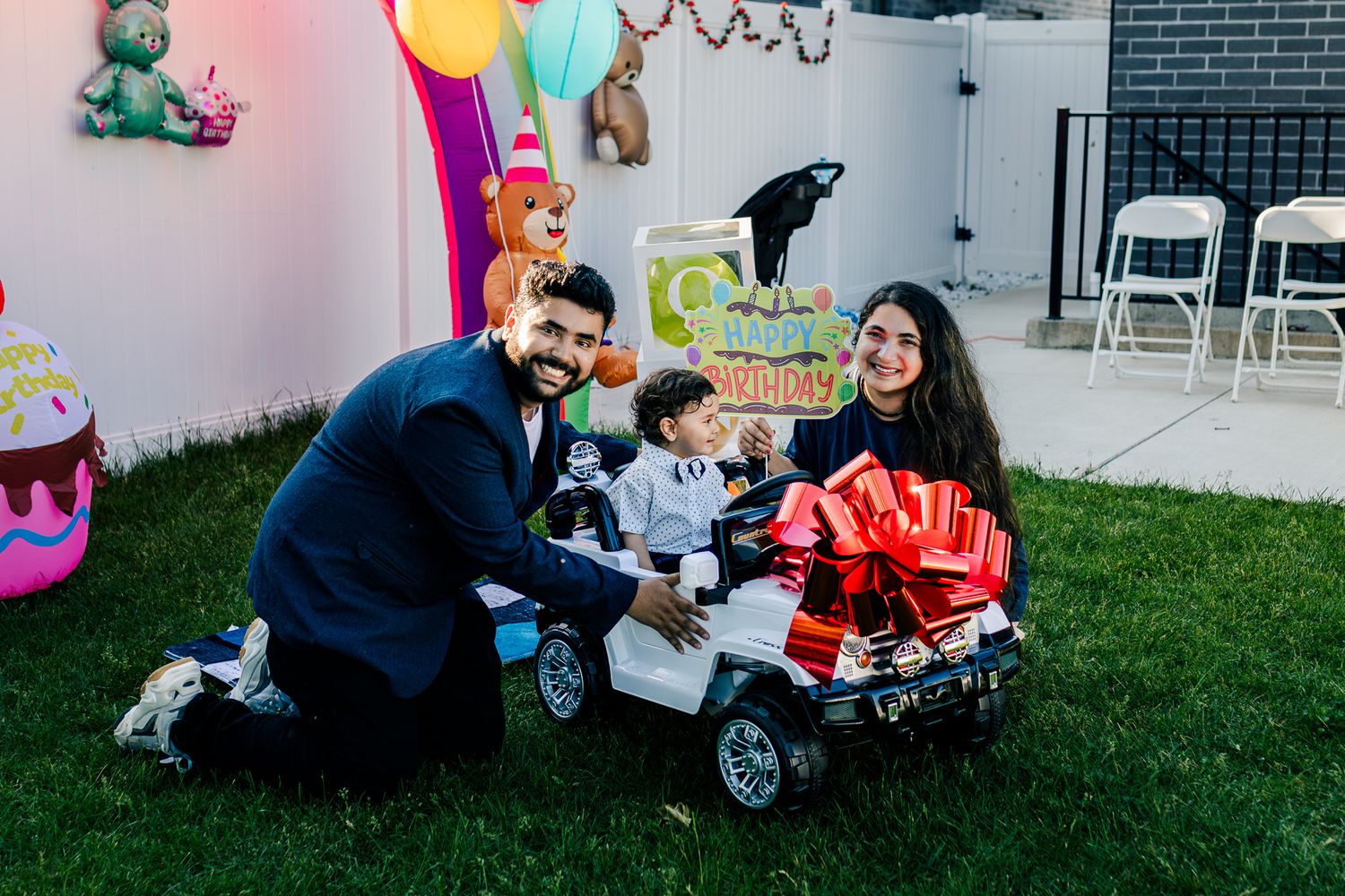 One year baby in a toy car next to his parents at his birthday party