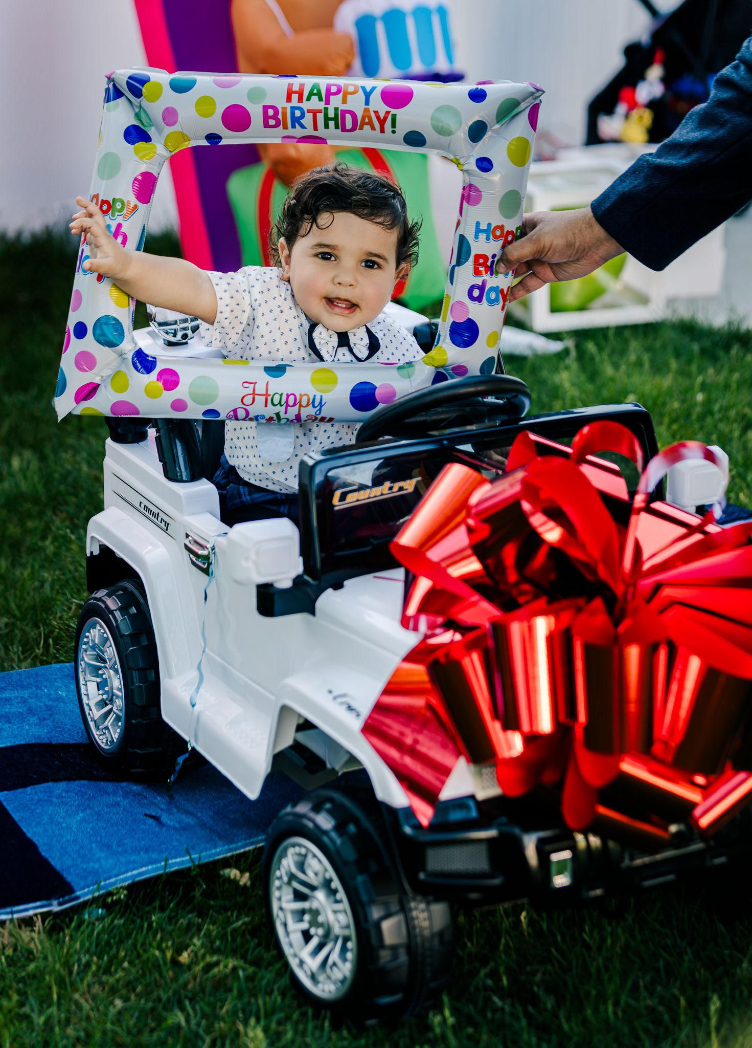 One year baby in a toy car at his birthday party