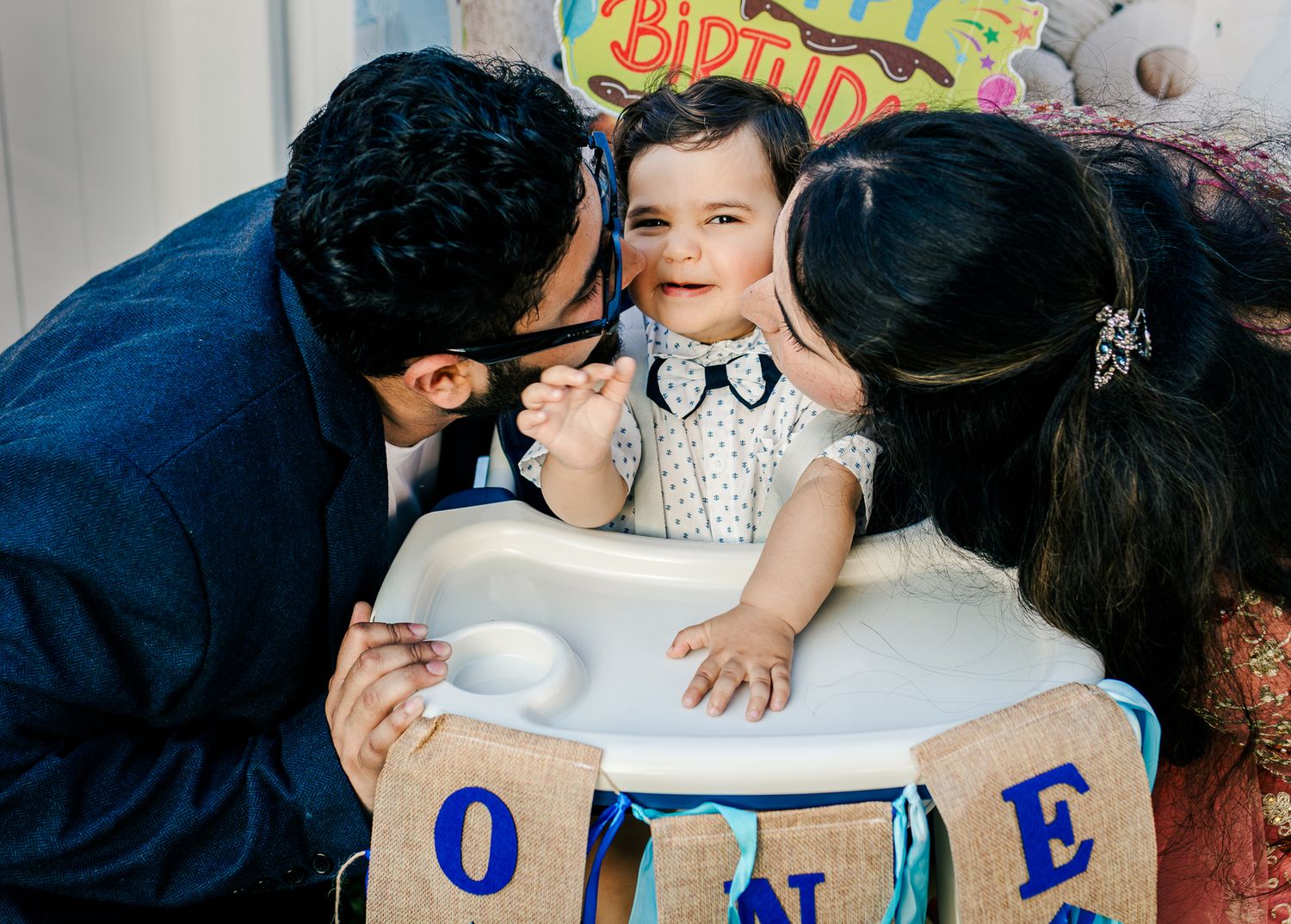 Mom and dad kissing baby boy's cheeks