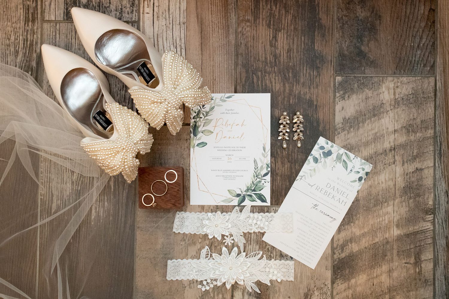 Wedding invitation suite and rings styled on rustic wooden surface with delicate details.