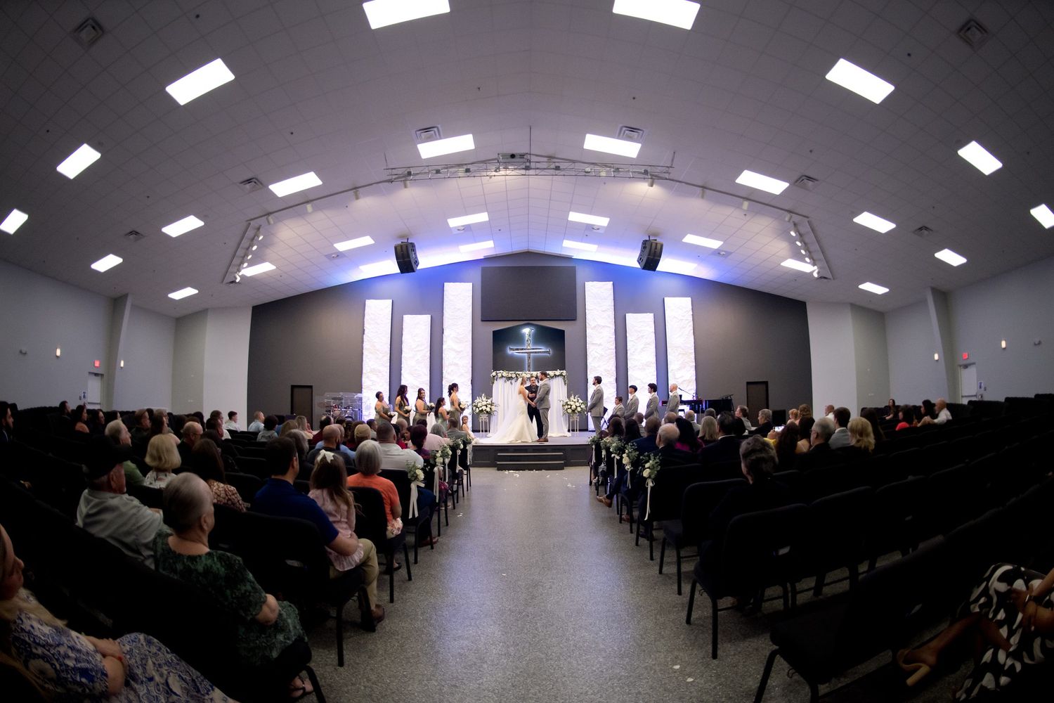 Wide angle view of modern church sanctuary during wedding ceremony.
