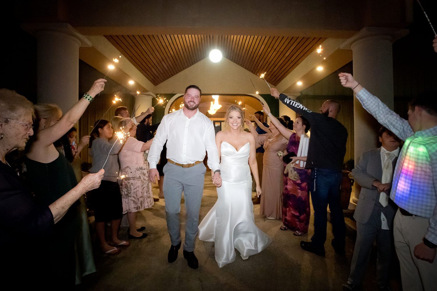 Wedding reception dance floor illuminated with party lights as guests celebrate.