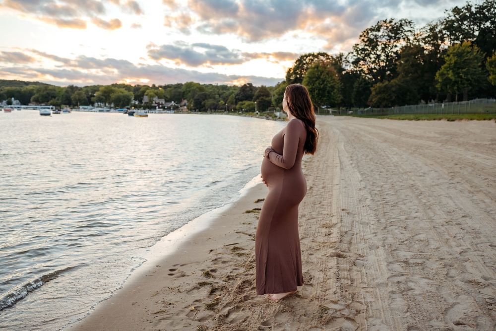 A scenic beach photoshoot at sunset with silhouettes against a golden sky and gentle waves along the shoreline.