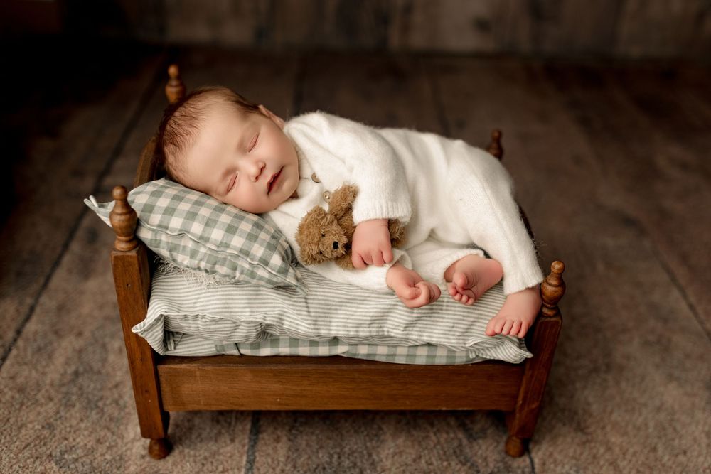 Newborn baby boy on small bed and green sheets with Tiffany Bergamino Photography in Marion indiana