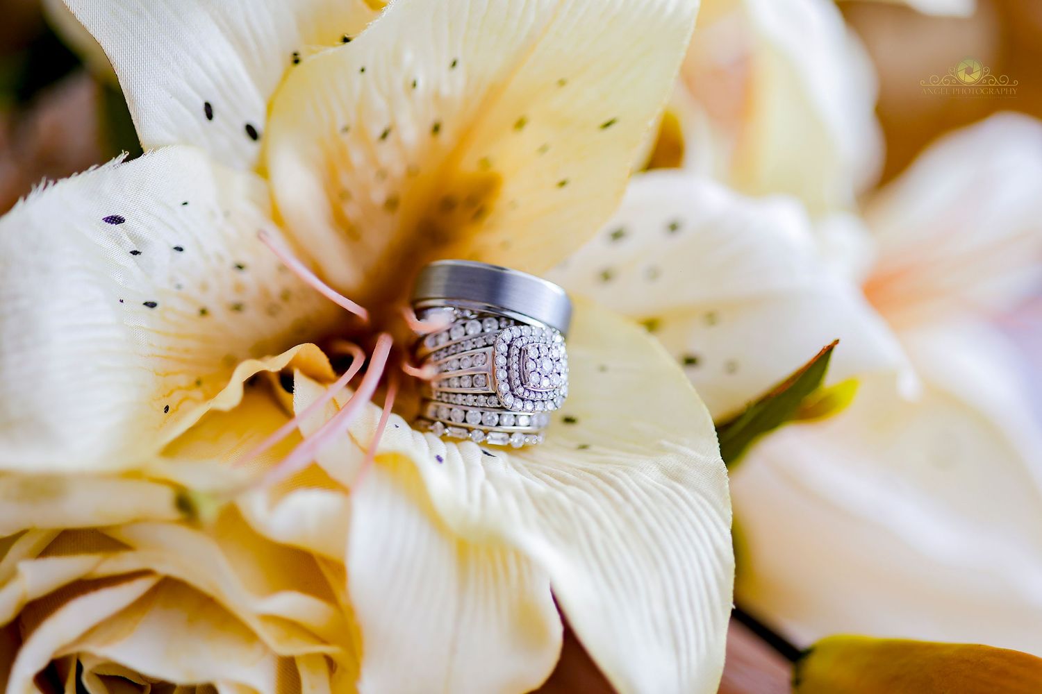 Close-up of a diamond engagement ring resting on white lily petals.