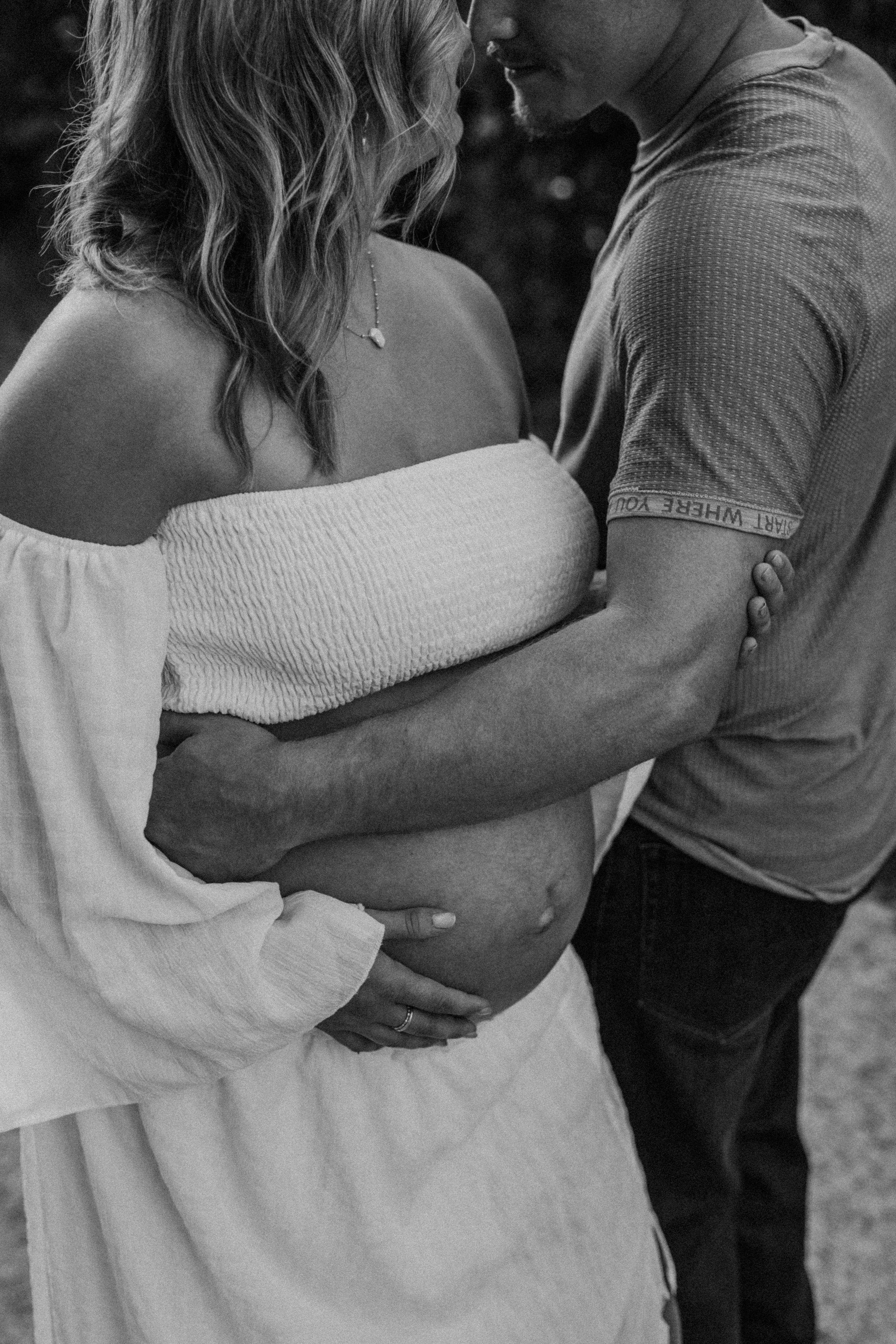 Intimate black and white maternity photos showing couple embracing.