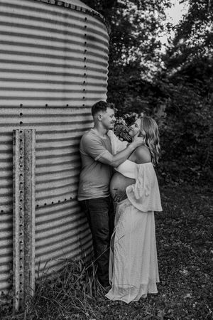 Romantic couple poses against a grain bin in black and white photo sequence.