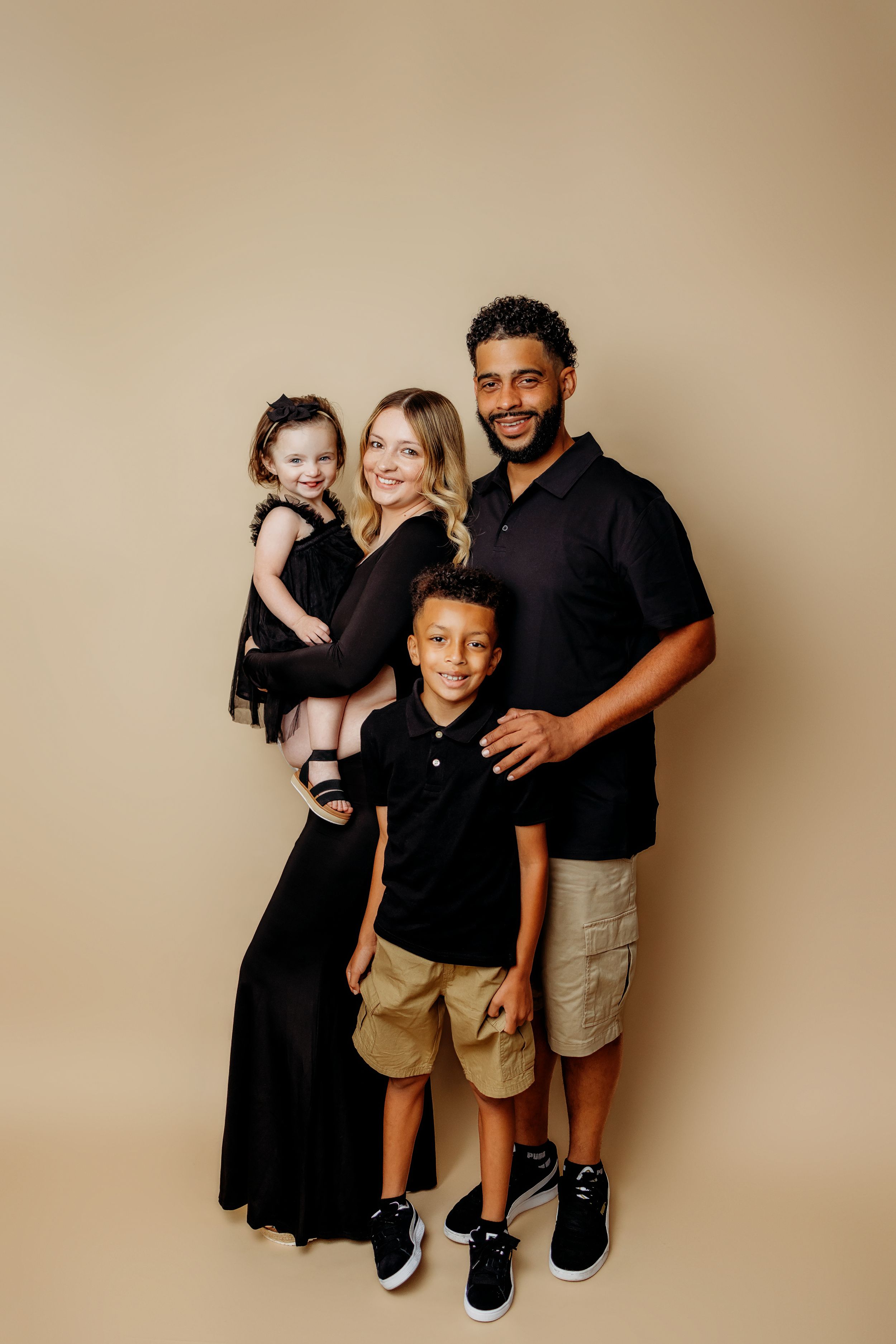 Family portrait series in coordinated black outfits against neutral backdrop.