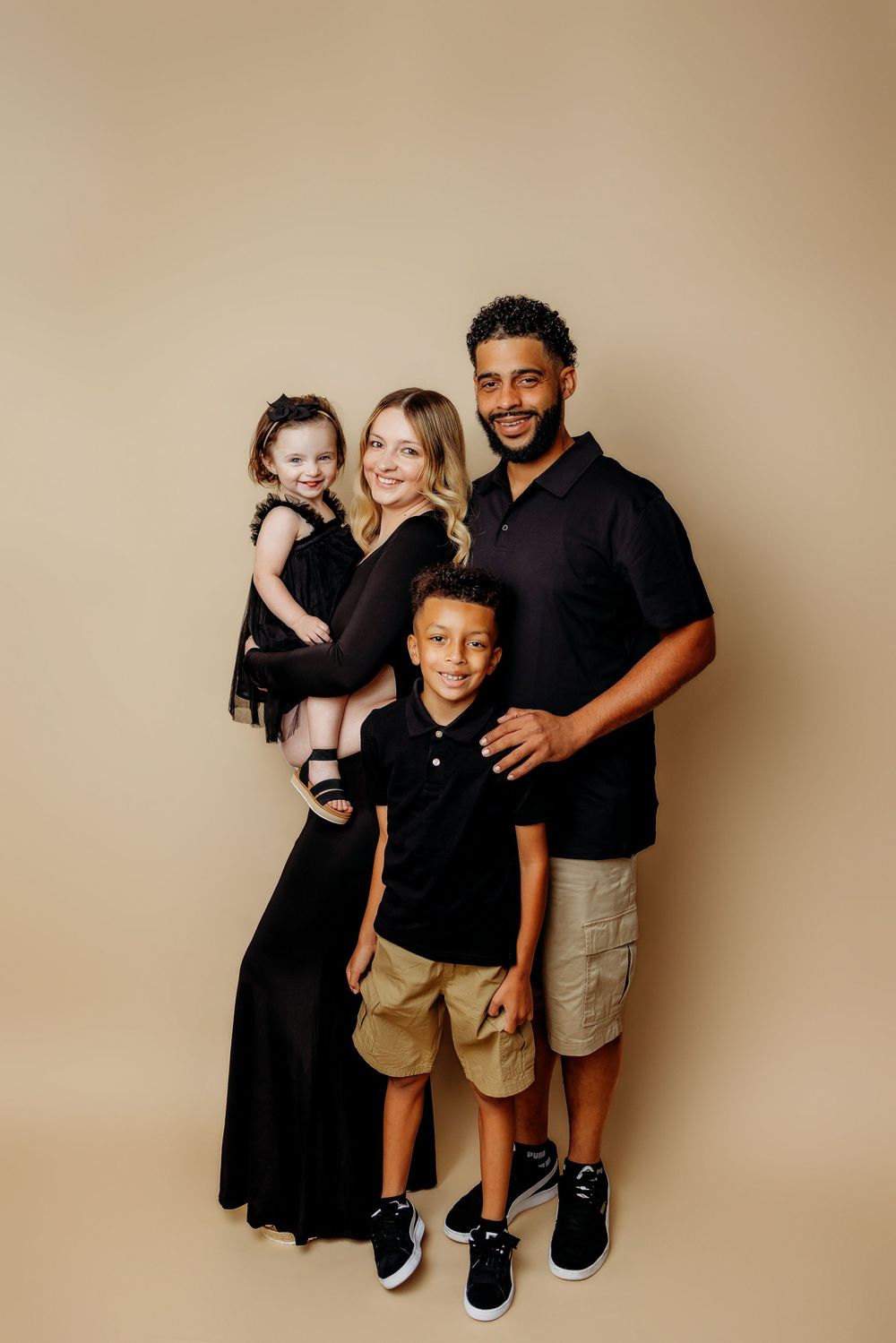 Family portrait series in coordinated black outfits against neutral backdrop.
