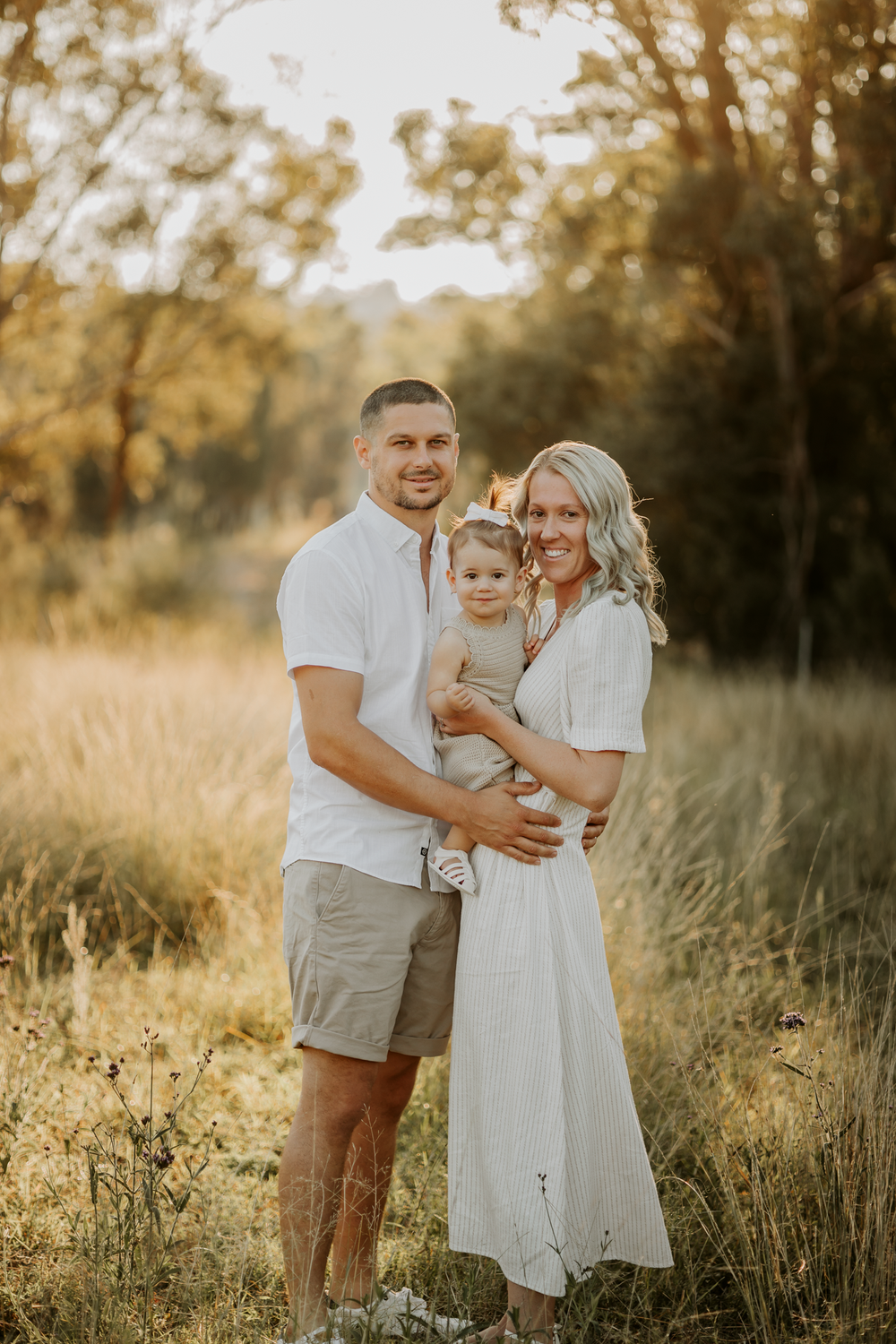 Family enjoying a warm sunset together in a golden grassy field.