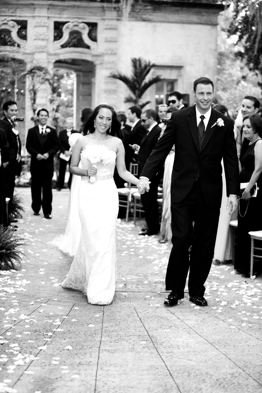 Black and white wedding sequence showing a flower girl dropping petals while walking down an aisle lined with guests.