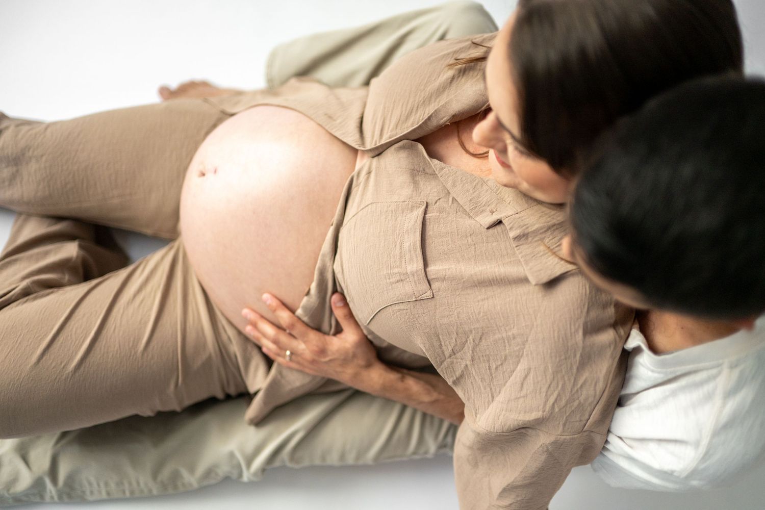 Side view maternity poses in neutral tones against white background.