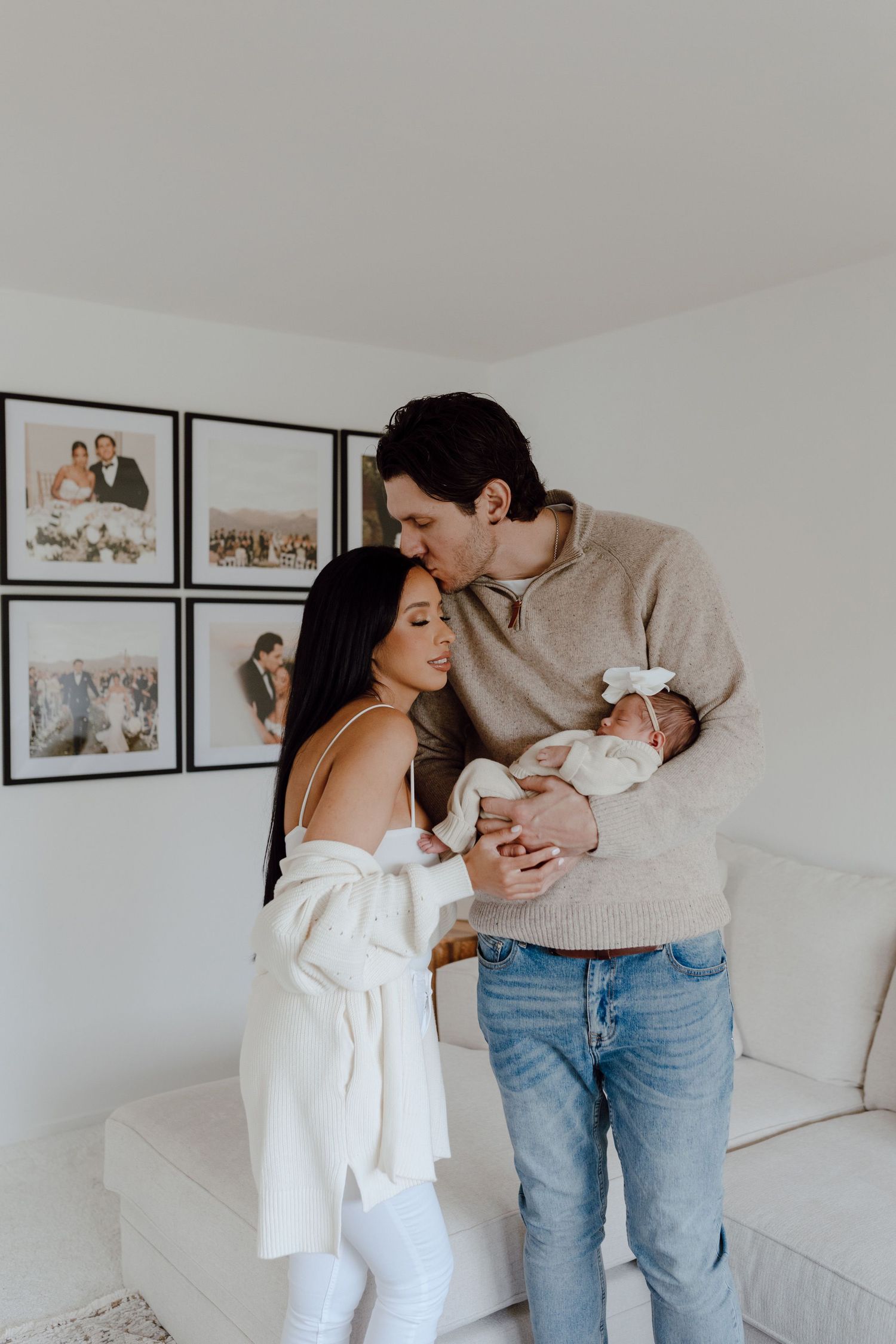 A tender moment shared with a newborn baby in a bright modern living room with family photos.