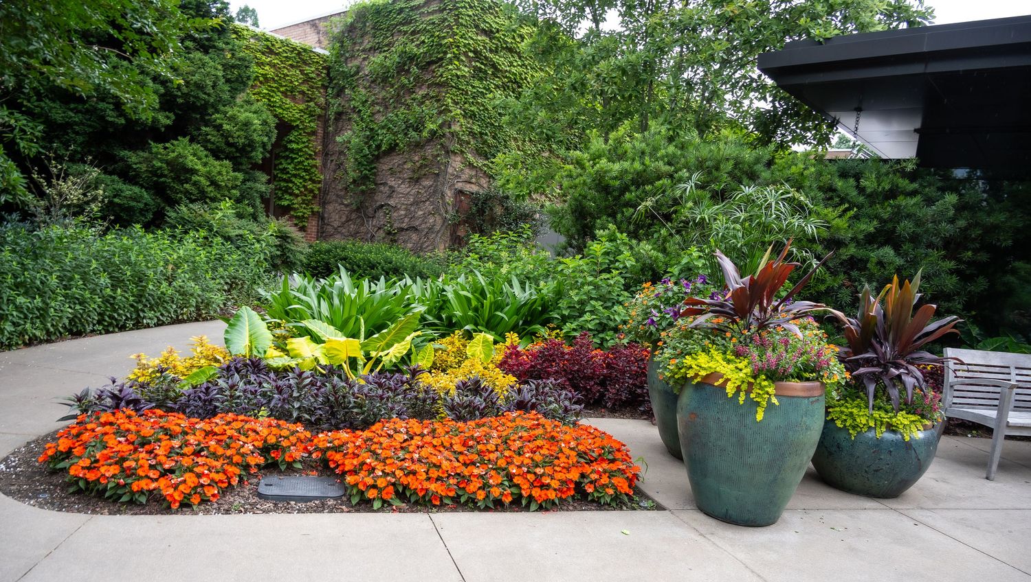 Colorful garden display with orange marigolds and tropical plants in blue ceramic containers.